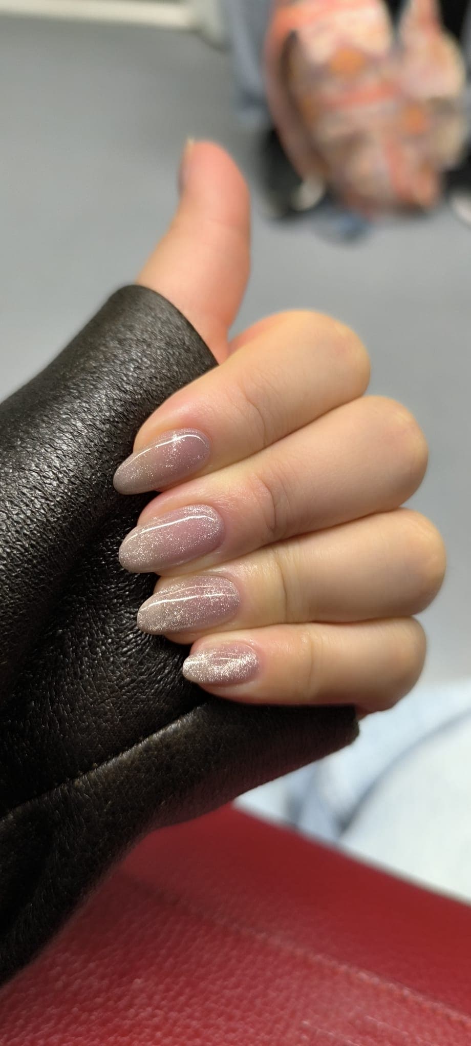 Manicura nude shimmer en almendra sobre cuero negro — trabajo real de Dany Nails